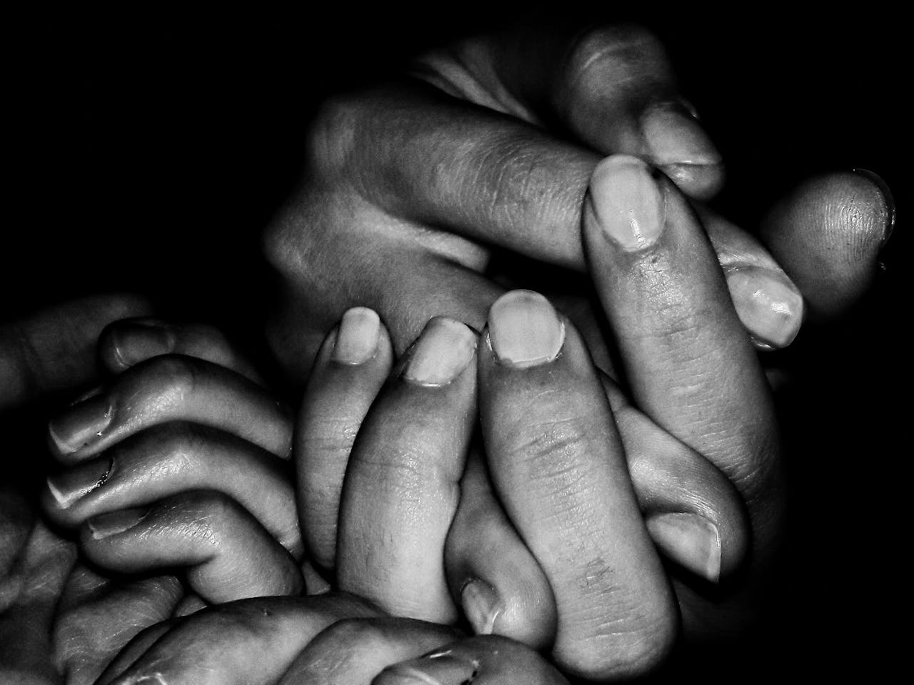 About A black and white close-up of family hands holding each other, symbolizing unity and support.